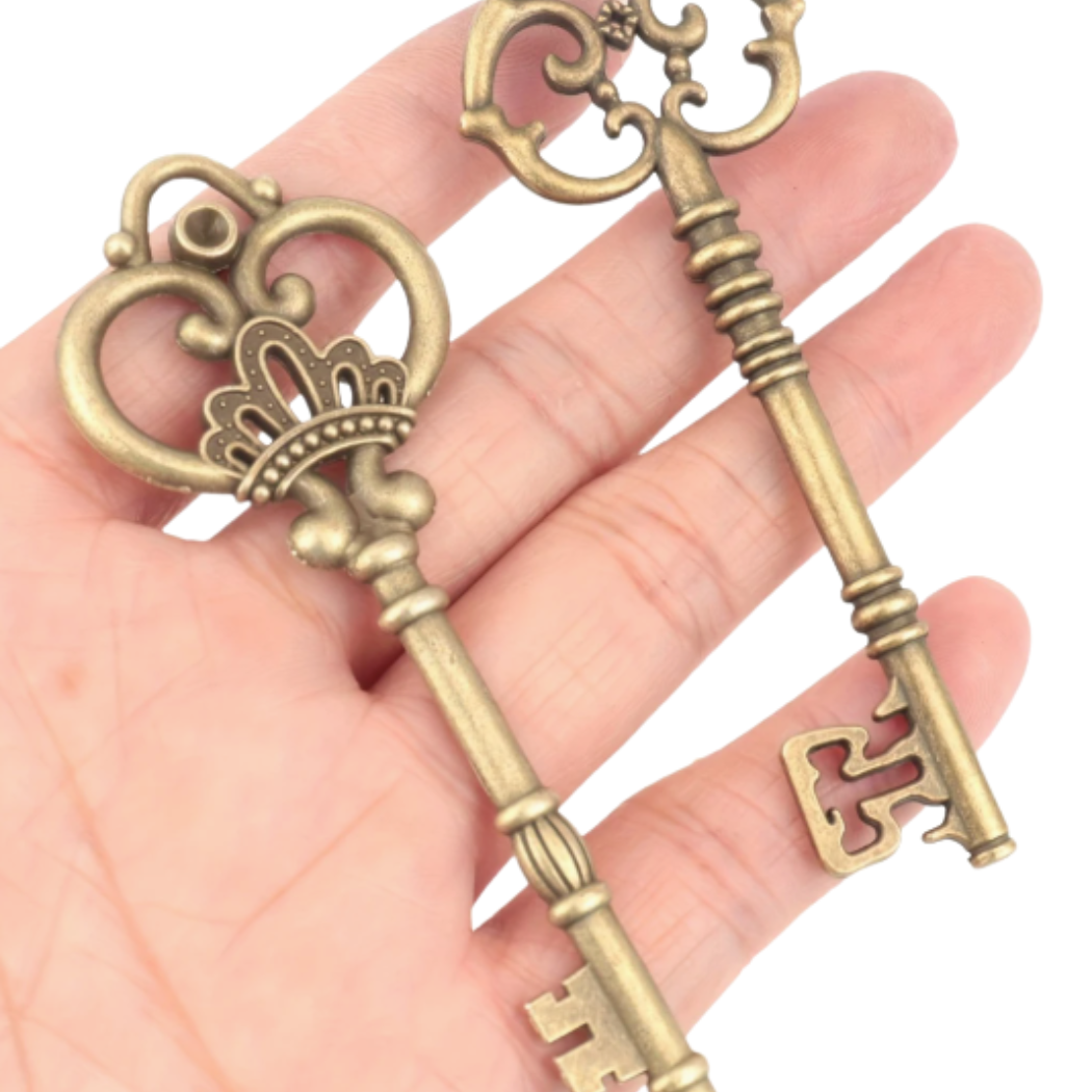 Two ornate brass keys held in a hand against a white background