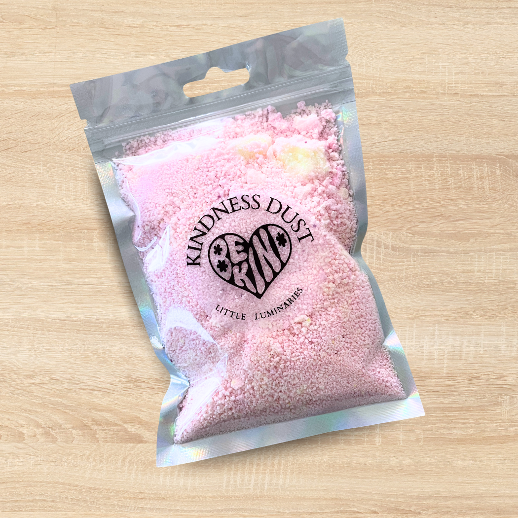 Packaged pink 'Kindness Dust' on a wooden surface