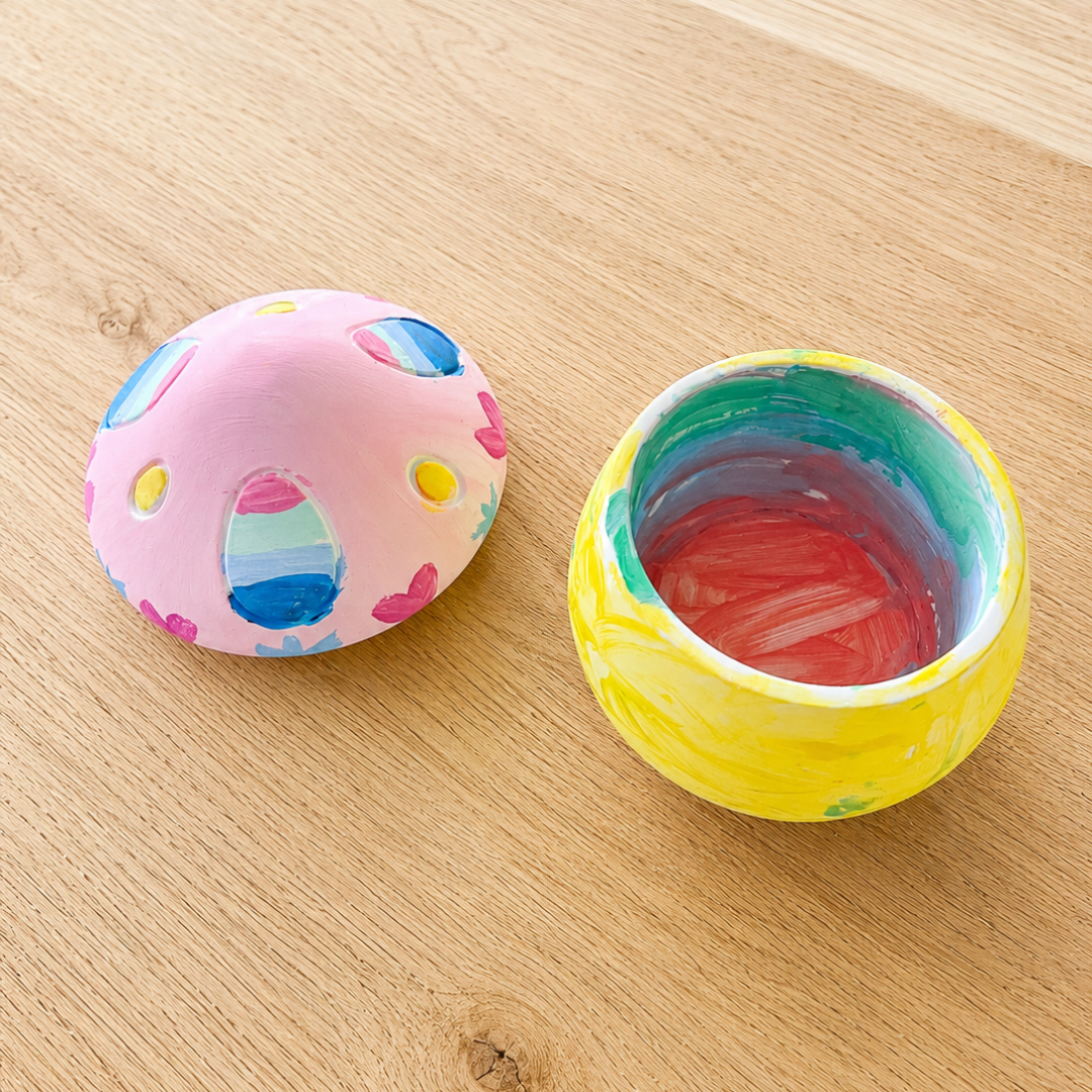 Colourful potion pot with a pink lid and yellow body on a wooden surface